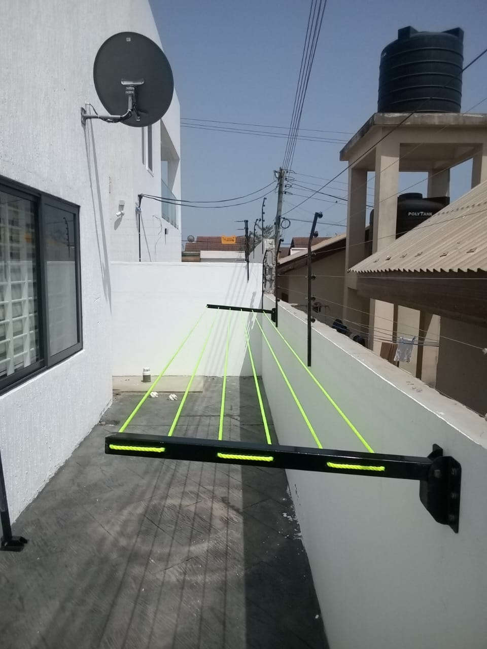 Foldable drying line fitted in a narrow side passage between an apartment block and a boundary wall