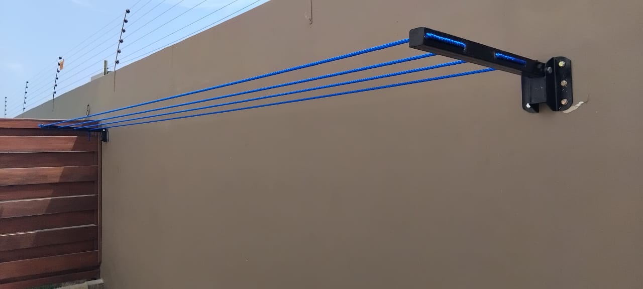 Foldable drying line with blue lines mounted on a wall beside a timber fence