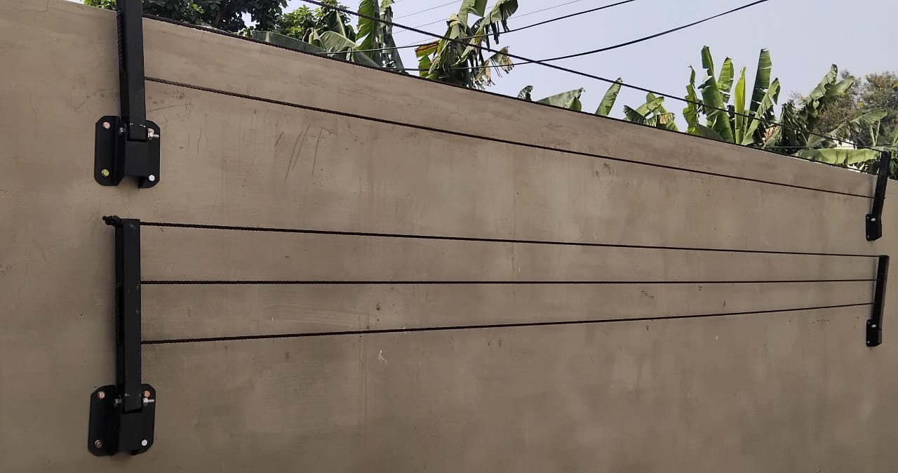 Foldable drying line folded flat against a compound wall, arms upright and lines held close to the render