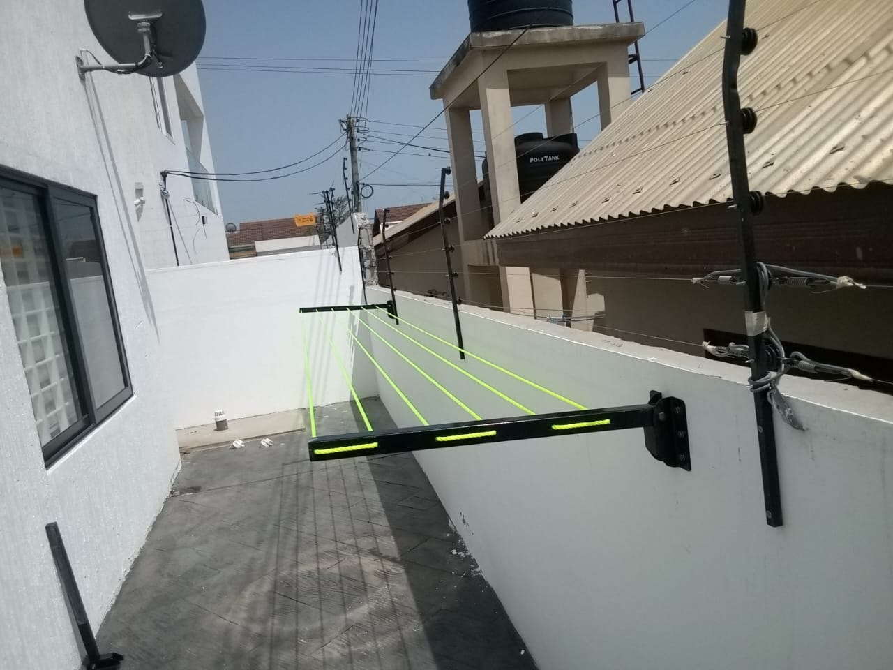 Foldable drying line spanning a narrow paved passage beside a house in Accra