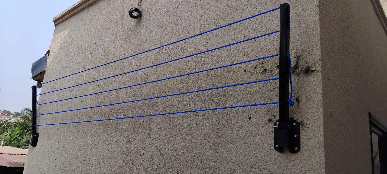 Six blue drying lines strung across a plastered wall from a black wall-mounted foldable arm